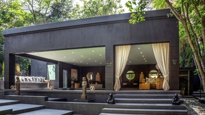 A modern building with a large glass facade, outdoor seating area, and steps leading to the entrance.