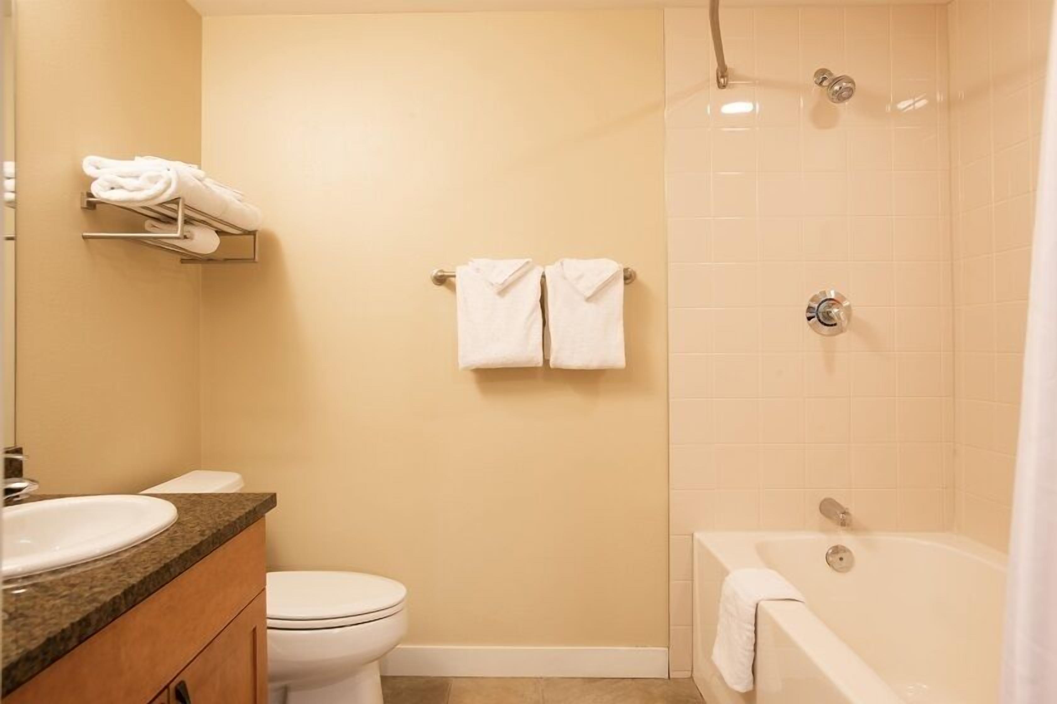 A bathroom with a toilet, sink, and bathtub. There are towels hanging on a rack and a shower curtain.
