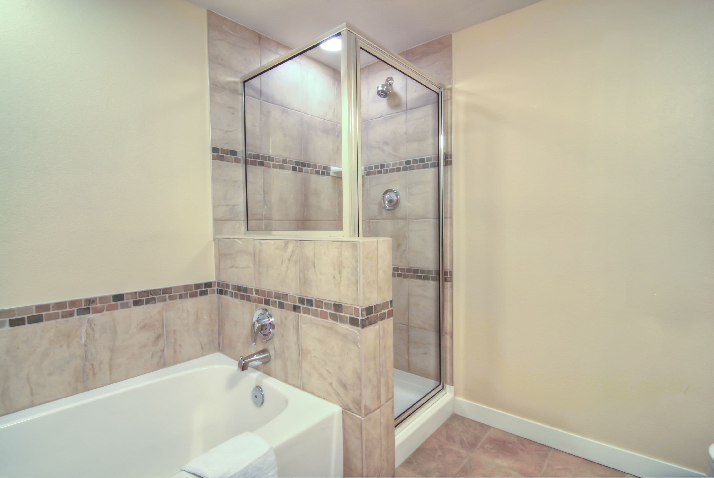 A bathroom with a bathtub, a glass shower enclosure, and tiled walls.