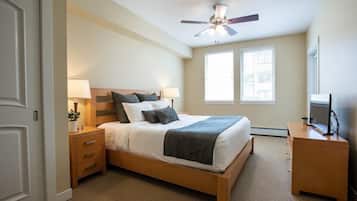 A bedroom with a bed, bedside tables, a ceiling fan, and a TV.