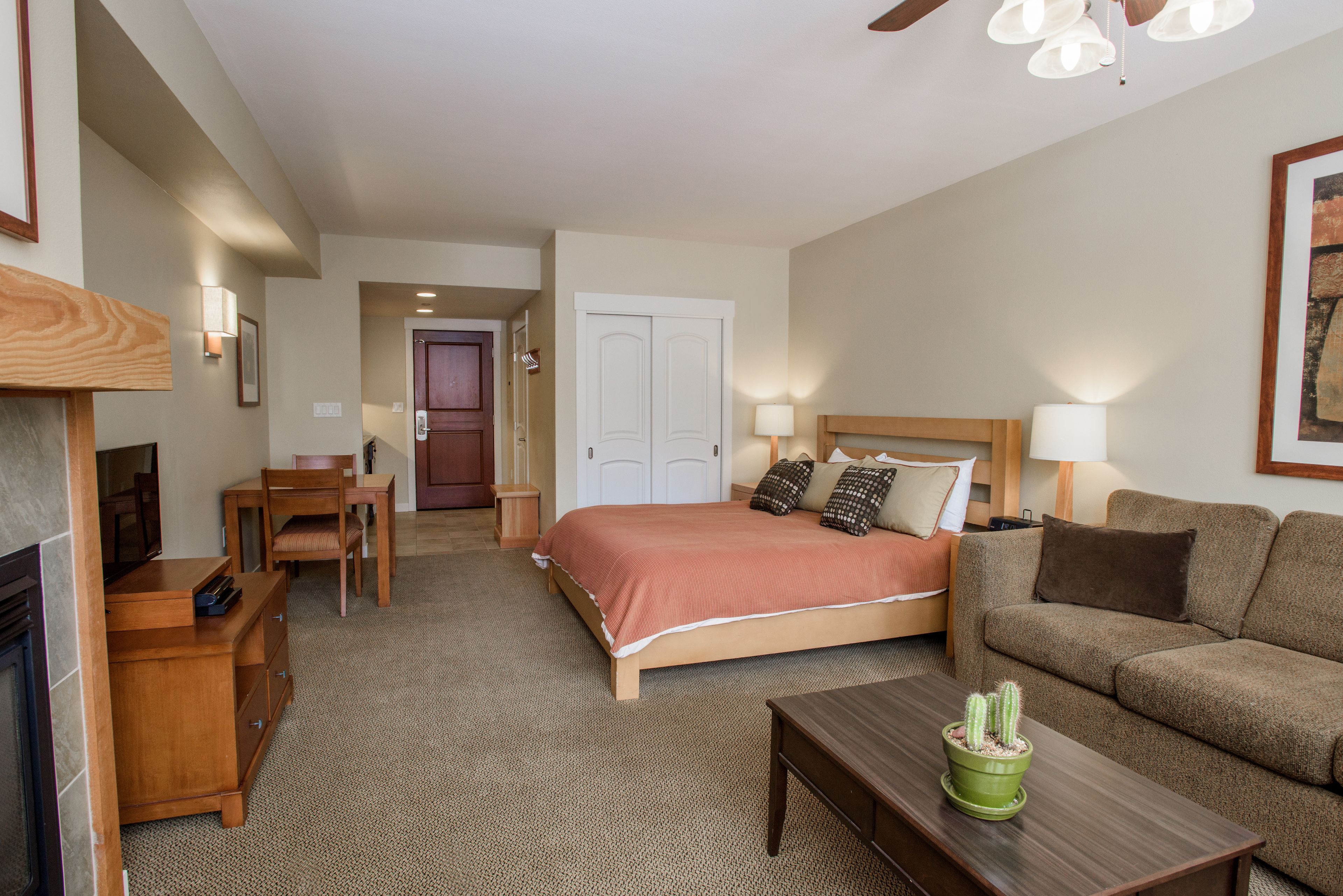 A hotel room with a bed, a sofa, a desk, and a coffee table.