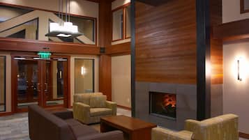 A lobby with a fireplace, seating area, and an exit sign.