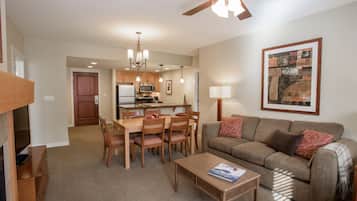 A spacious living area with a dining table, chairs, a sofa, and a ceiling fan.