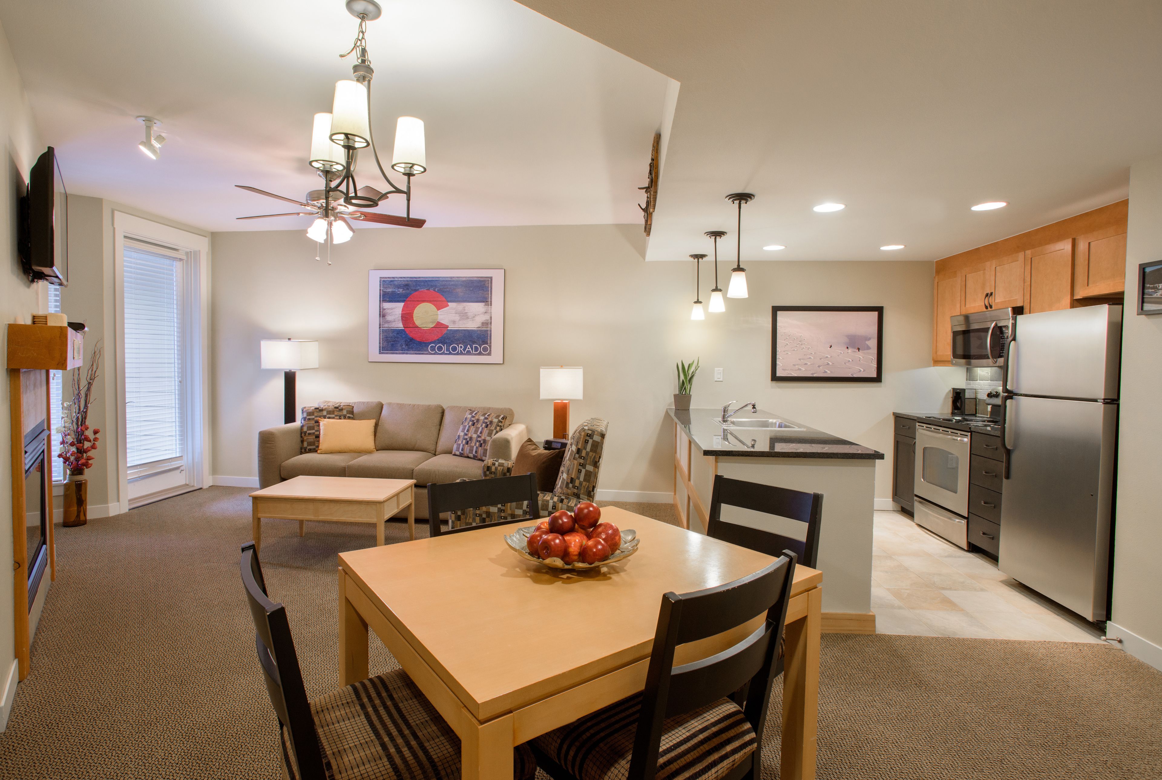 A modern kitchen with a dining area, a sofa, and a television.