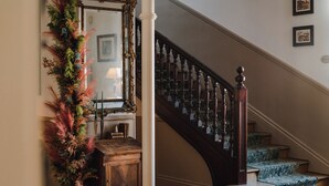 A staircase with a wooden handrail and steps, a mirror with a decorative frame, and a wall with framed pictures. - Hotel Edouard VII (Biarritz)