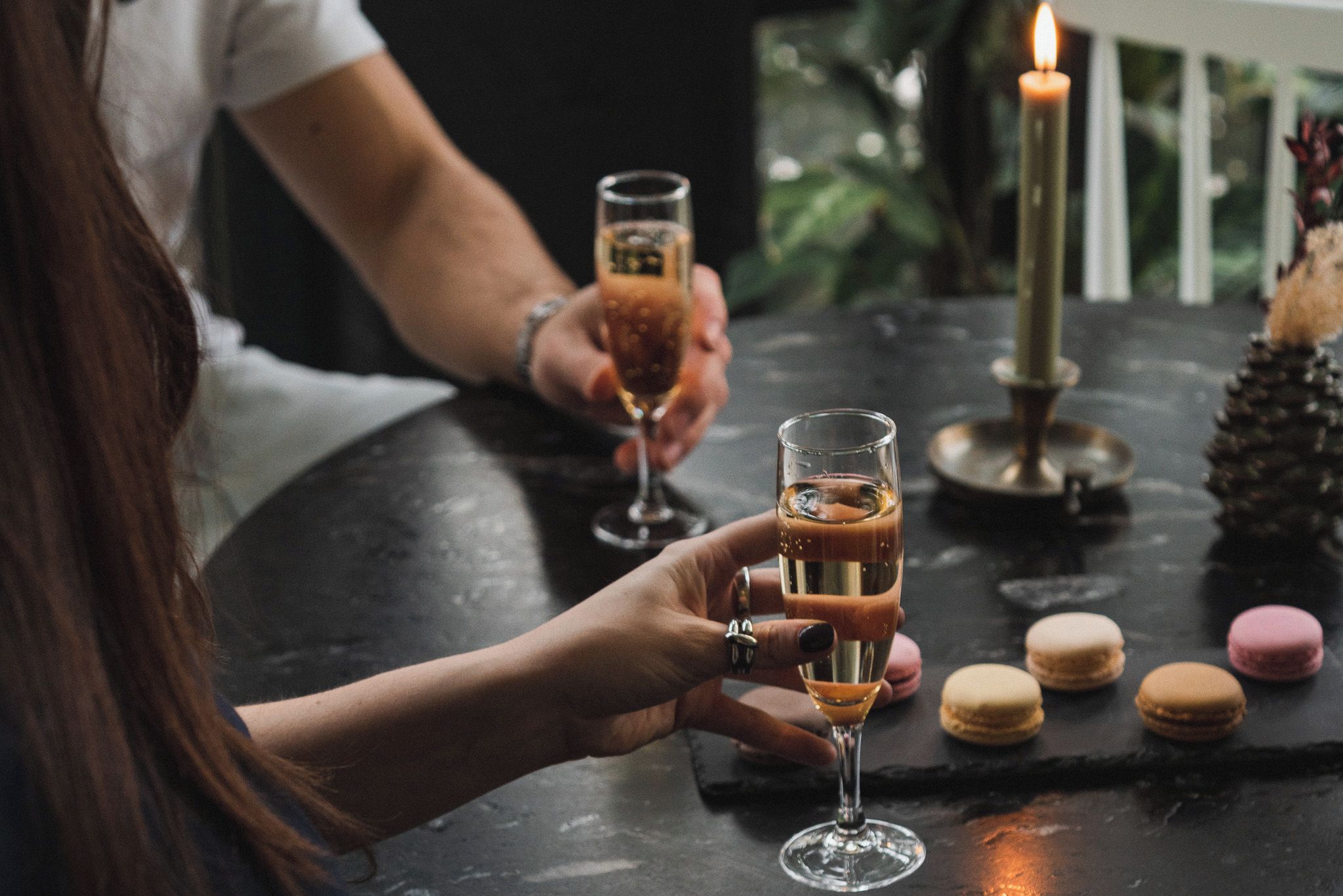 A table with two glasses of a beverage, a candle, and macarons.