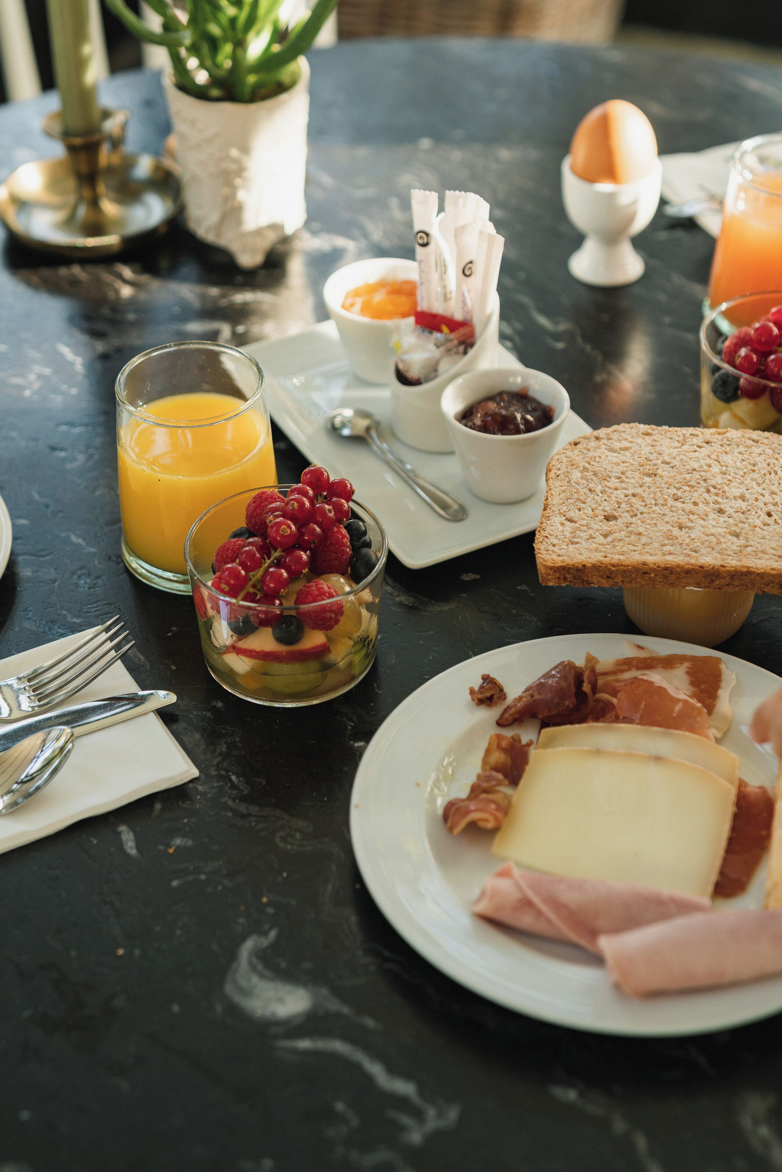 Taula de l'esmorzar amb diferents aliments, com ara torrades, ous i un got de suc d'aranja.