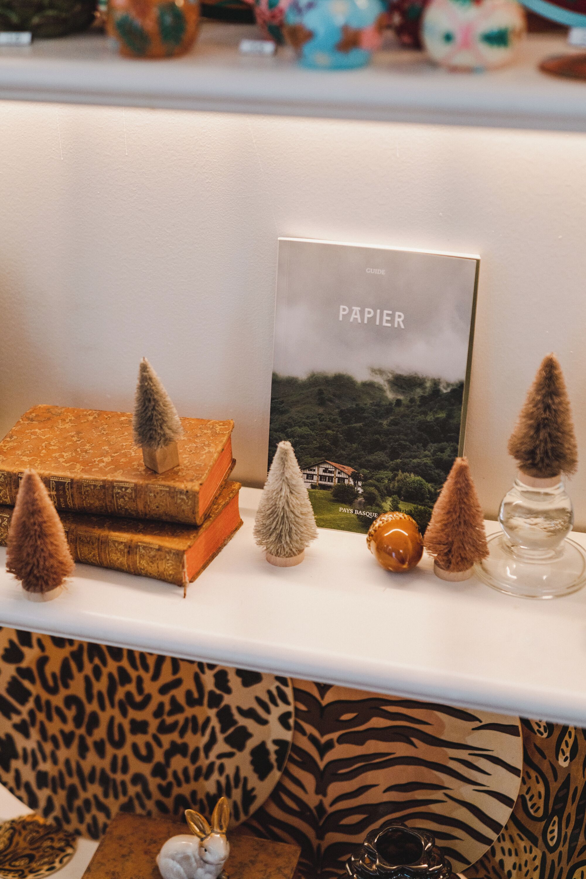 Une étagère ornée de divers objets décoratifs, notamment des livres, un tableau encadré et de petits arbres.