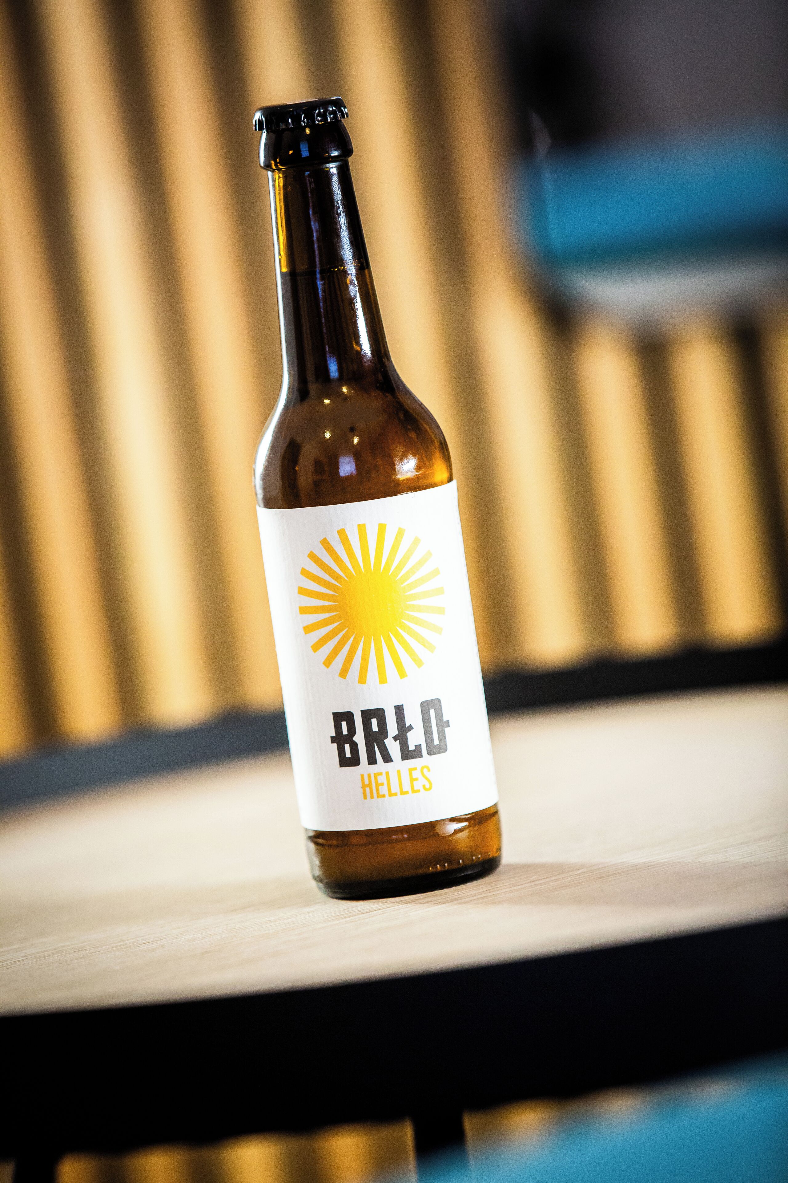 Una botella de cerveza con una etiqueta que dice "Brod Helles" sobre una superficie de madera.