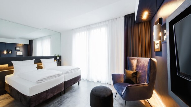 Una habitación de hotel moderna con cama, zona de estar y televisor.