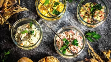 Tres frascos de vidrio con ensaladas de distintos ingredientes, rodeados de espigas de trigo y un pan sobre una superficie texturizada.