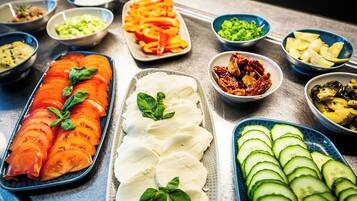 Variedad de alimentos dispuestos en una mesa, incluyendo tomates en rodajas, pepinos y otras verduras.