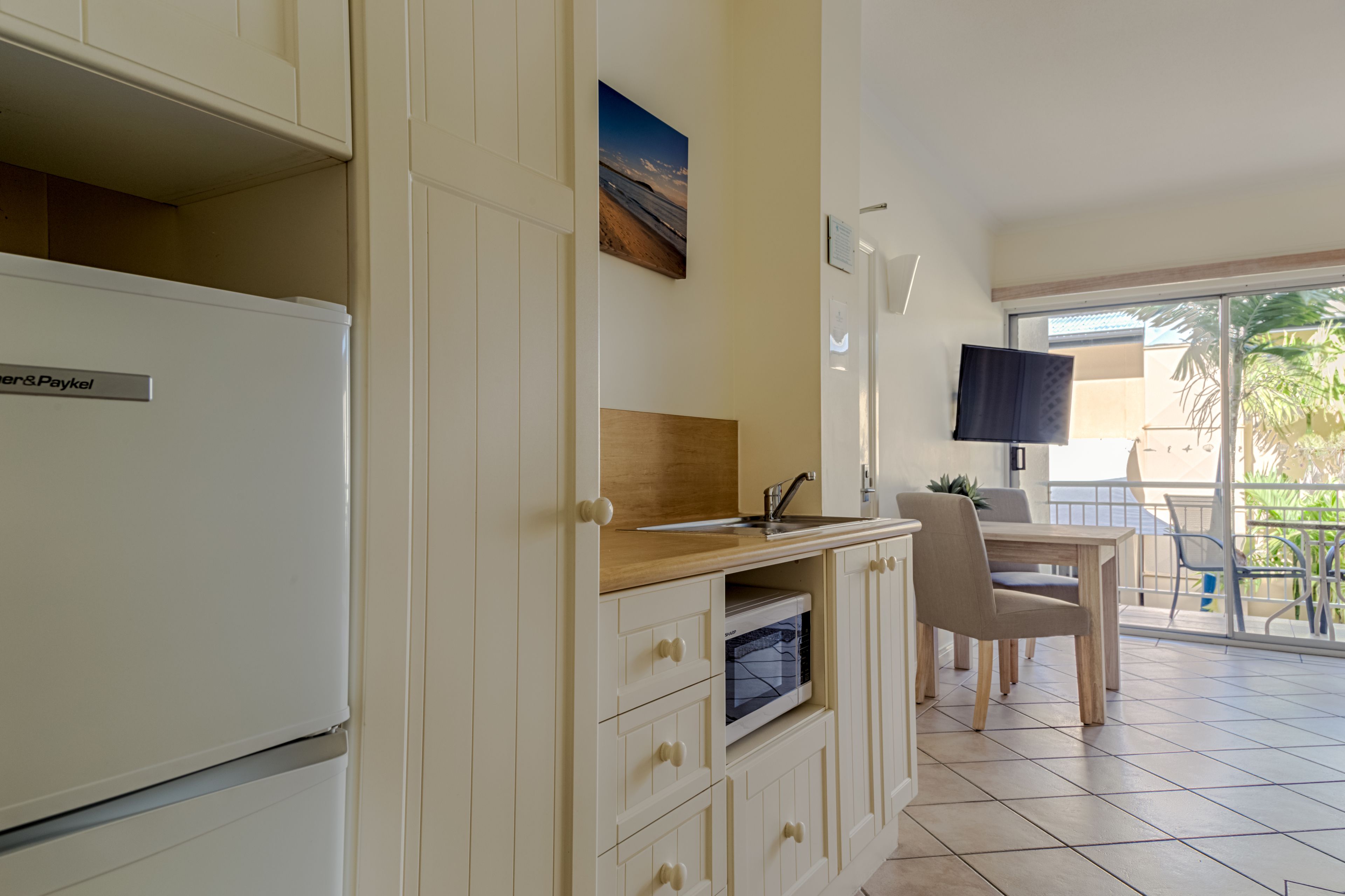 A compact kitchen with a refrigerator, wooden countertop, and a dining area with a table and chairs.