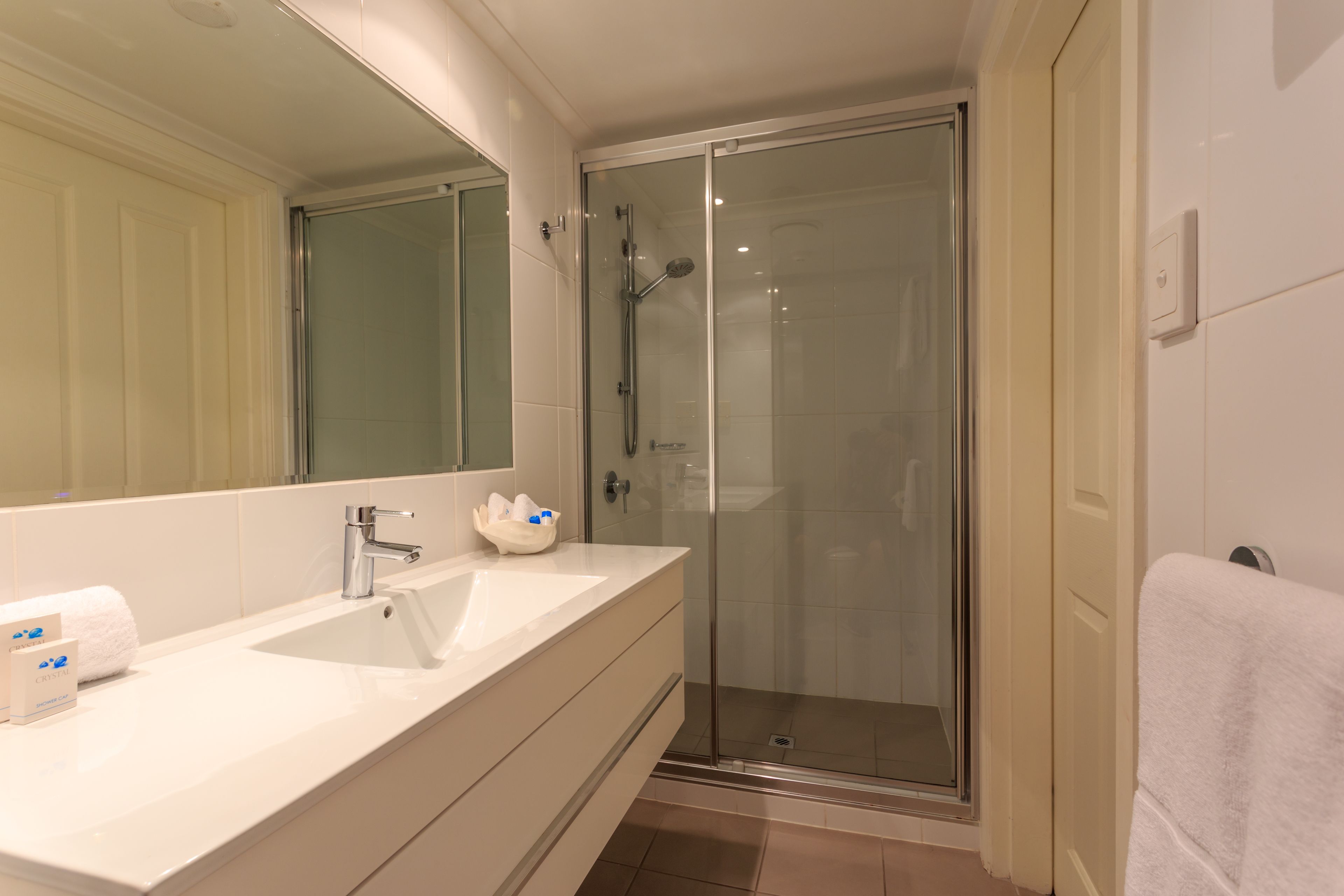 Une salle de bain avec un grand miroir, un lavabo et un espace douche.