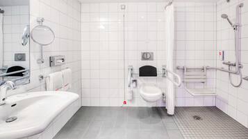 Un baño moderno con lavamanos, inodoro y zona de ducha blancos.