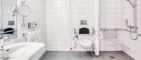 Un baño moderno con lavamanos, inodoro y zona de ducha blancos.