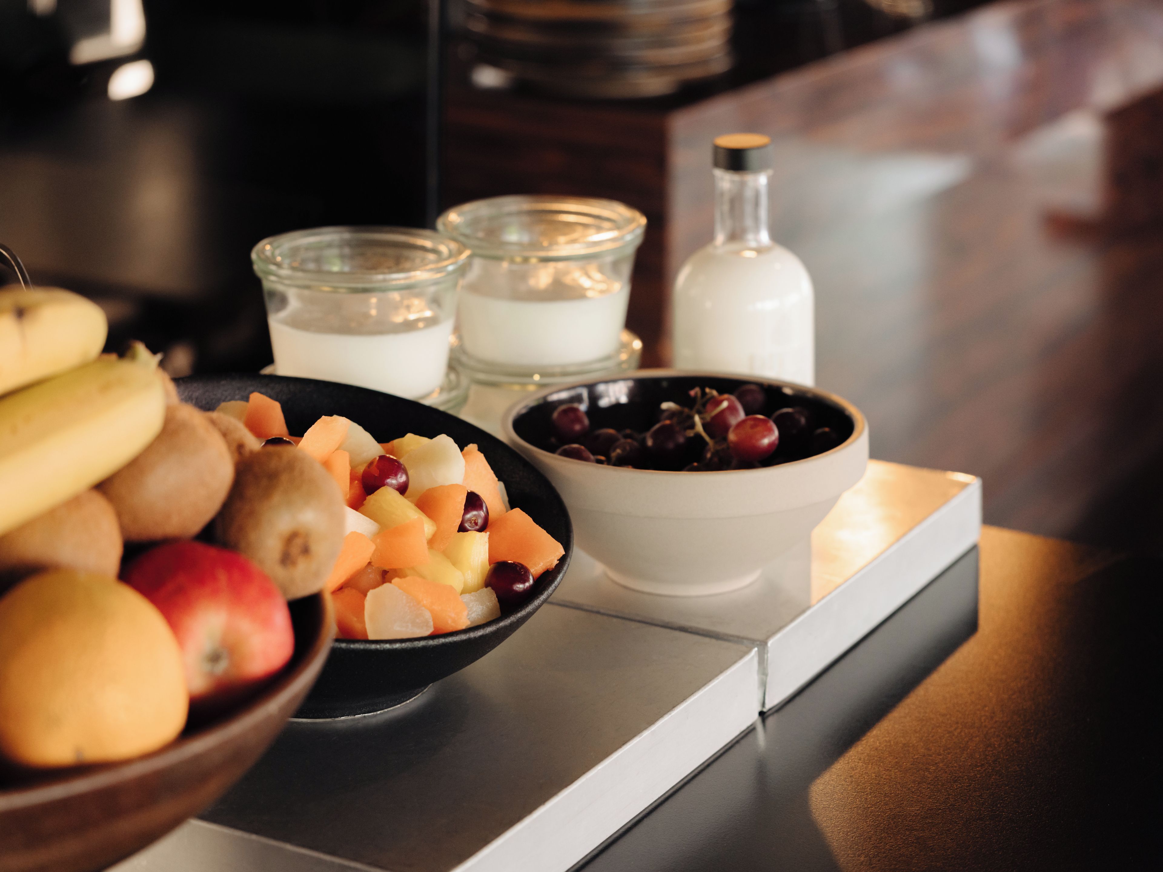 Mesa posta para o café da manhã com frutas variadas e uma vela.