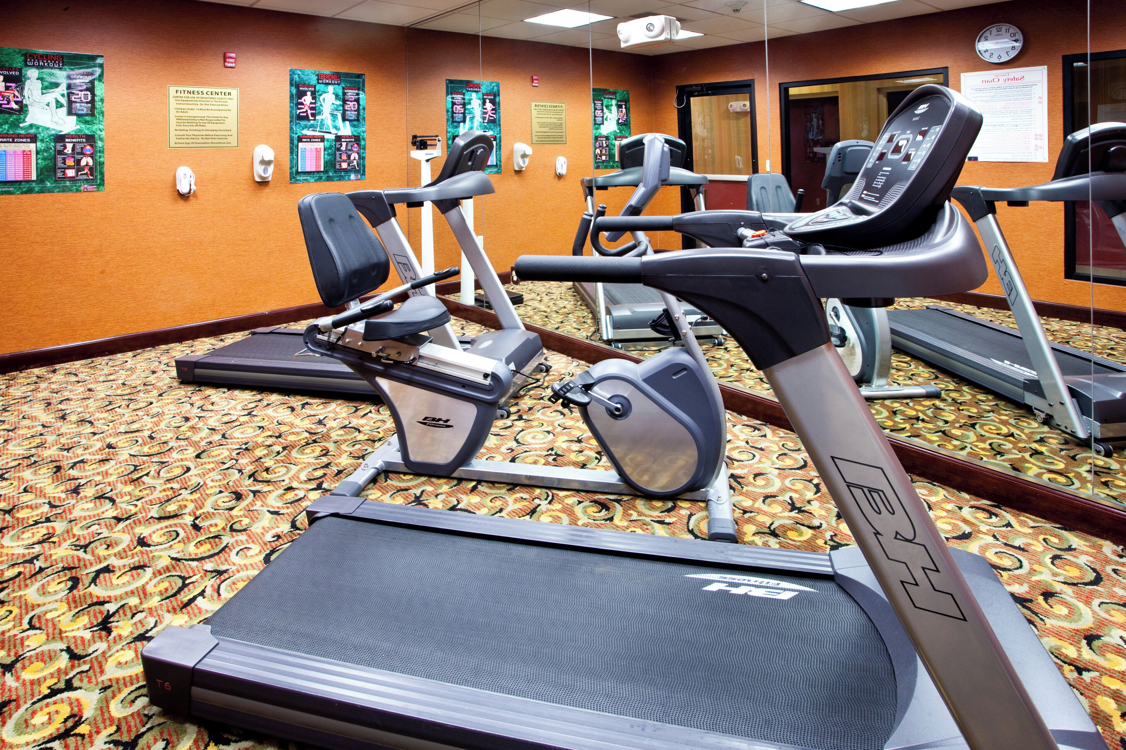 A fitness center with treadmills, stationary bikes, and a mirrored wall.