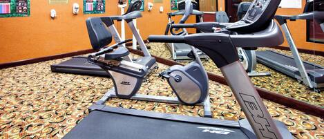 A fitness center with treadmills, stationary bikes, and a mirrored wall.