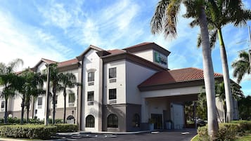 A hotel with a two-story structure, a red-tiled roof, and a parking lot.