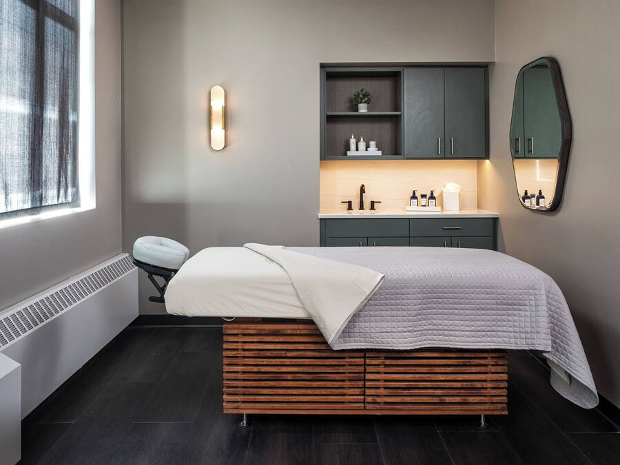 Un dormitorio moderno con cama, almacenamiento integrado, tocador y un espejo grande.