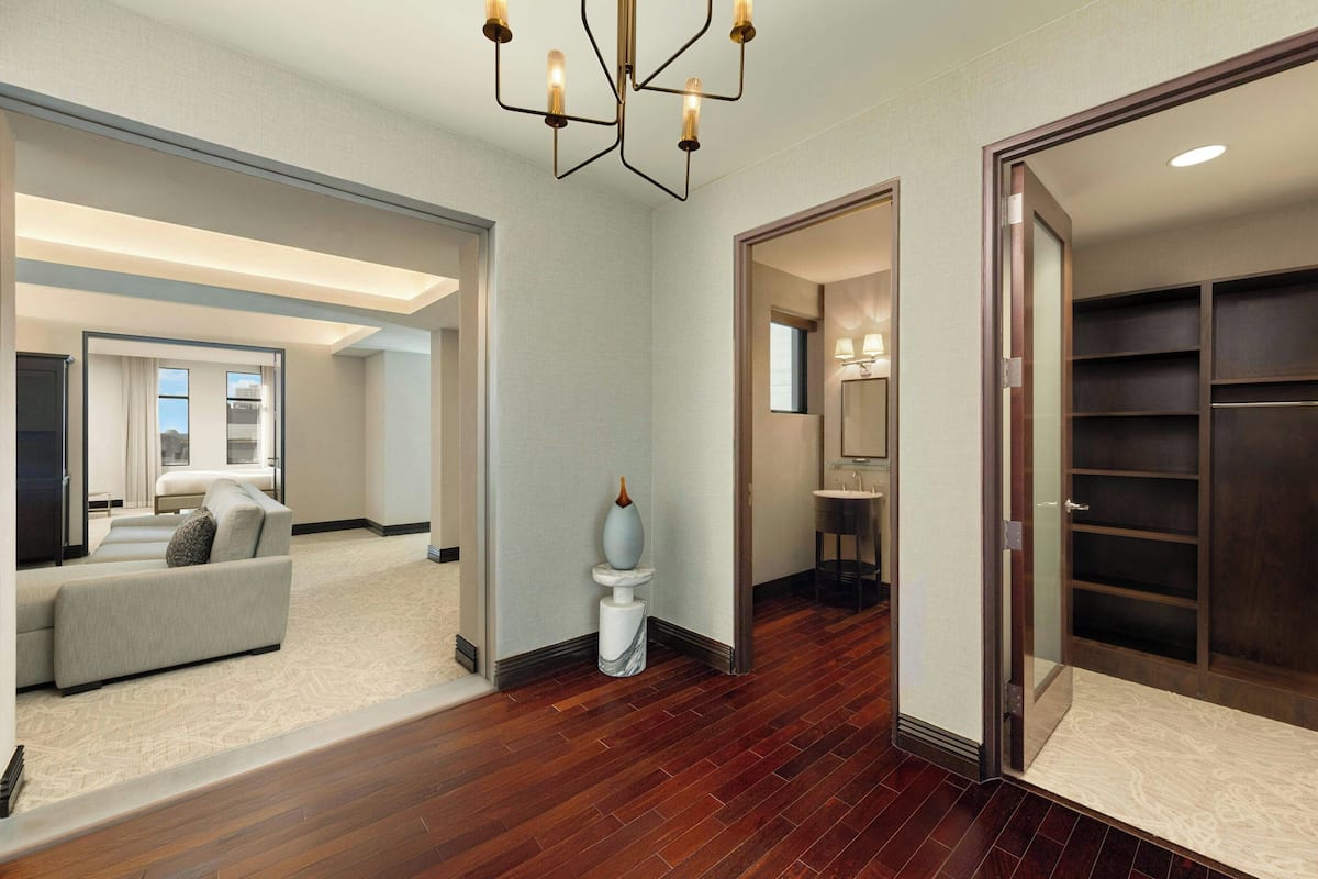 A spacious hallway with a sofa, a marble pedestal, and a walk-in closet.
