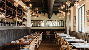 A restaurant with long wooden tables, wicker chairs, and hanging light fixtures. - Hotel Ivy, a Luxury Collection Hotel, Minneapolis (Minneapolis)