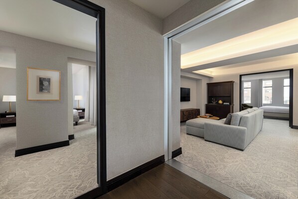 A modern hotel room with a large mirror, a grey sofa, a flat-screen TV, and a wooden cabinet. - Hotel Ivy, a Luxury Collection Hotel, Minneapolis (Minneapolis)
