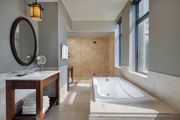 Un baño moderno con una bañera grande, un tocador con espejo y una zona de ducha.