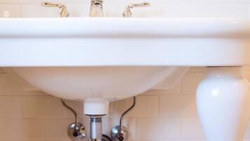 A white bathroom sink with chrome fixtures and a white tiled wall.