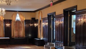 Um quarto espaçoso com piso de madeira polida, portas de madeira escura e um grande candelabro.