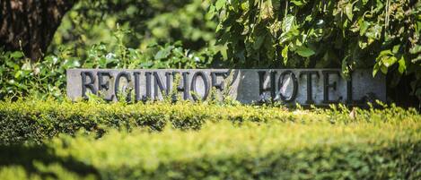 A sign for the Reginhof Hotel surrounded by lush greenery.