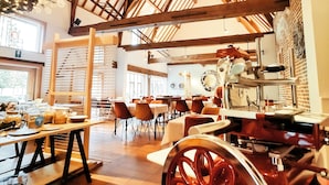 A restaurant interior with wooden beams, tables, chairs, and a vintage cart. - Begijnhof Hotel (Leuven)
