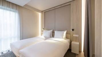 A hotel room with a large bed, a bedside table, and a window with curtains.