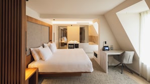 A modern hotel room with a large bed, a desk, and a shower area. - Begijnhof Hotel (Leuven)