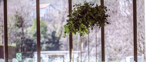 A dining table set for a meal with white chairs, a green tablecloth, and a floral centerpiece.