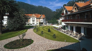 Un hôtel avec un chemin de pierre menant à une cour intérieure dotée d’un espace salon extérieur et offrant une vue sur une montagne.
