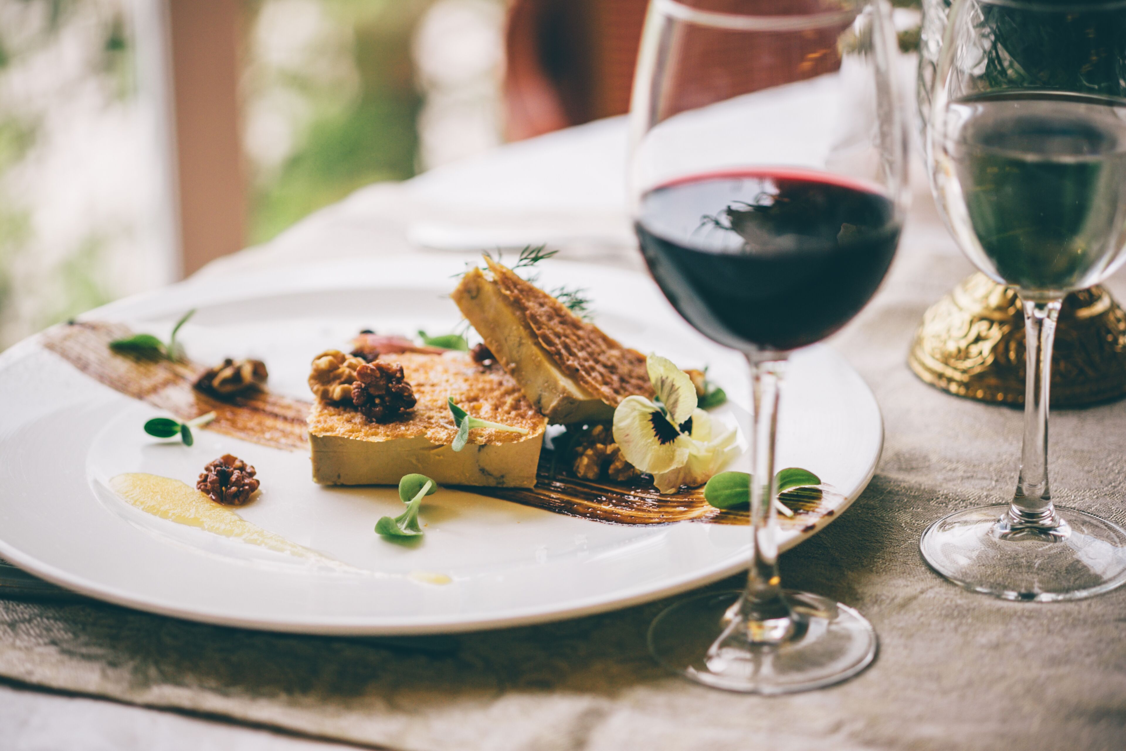 Un plato de comida con una copa de vino tinto sobre una mesa.
