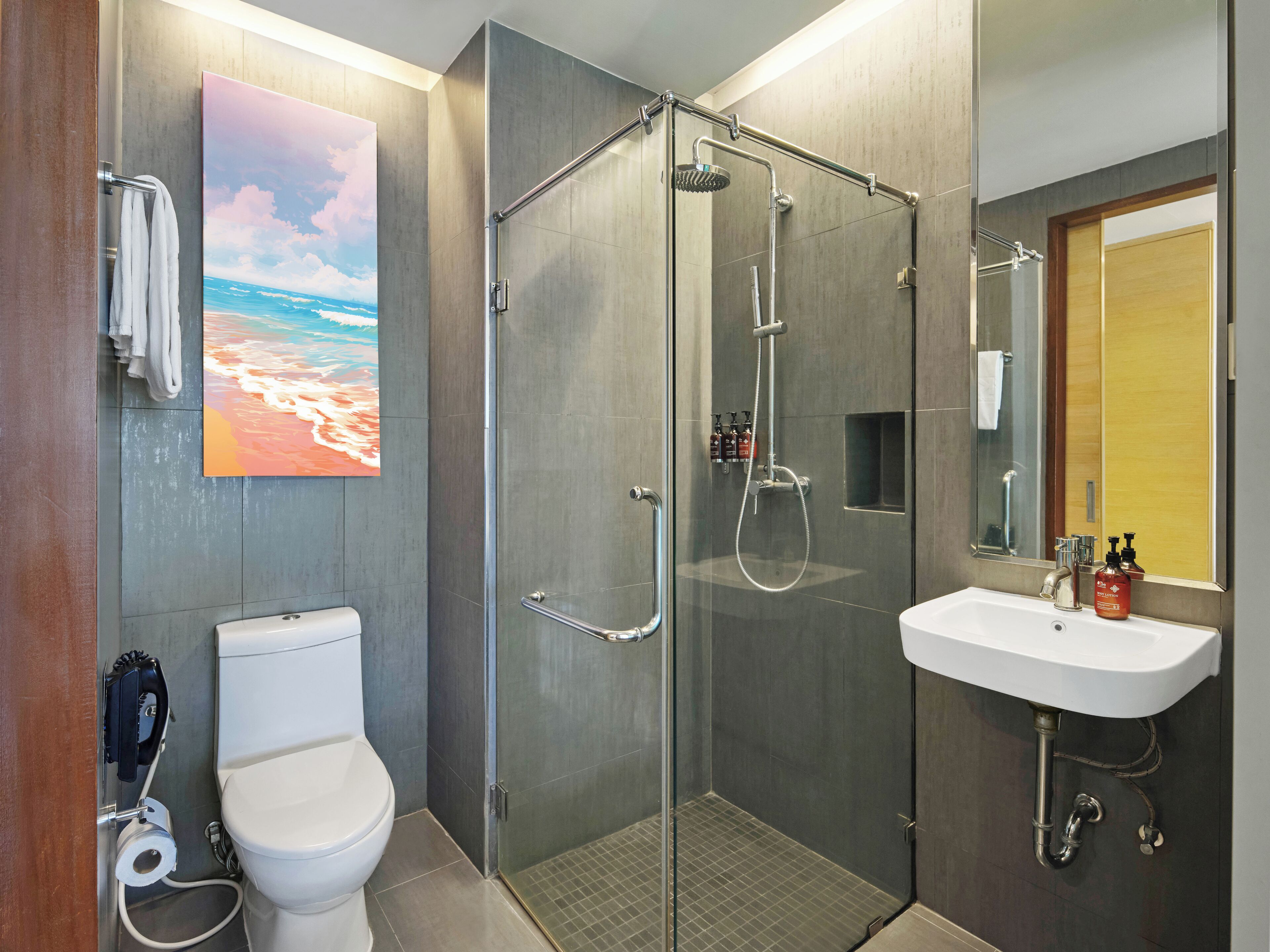 A modern bathroom with a glass-enclosed shower, a toilet, and a sink with a mirror.