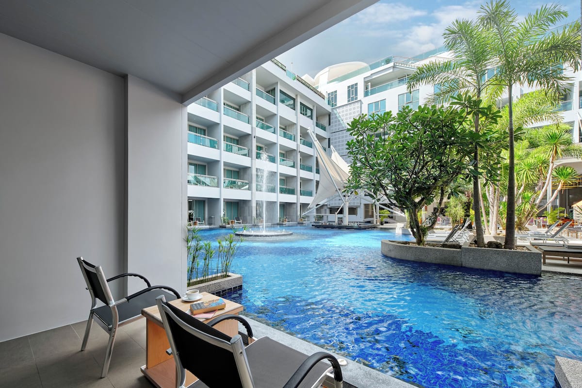 A modern hotel with a pool area, including lounge chairs and a dining table.
