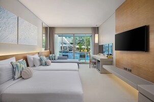 Habitación de hotel moderna con dos camas, un escritorio, un televisor de pantalla plana y vistas a una piscina y zona exterior.