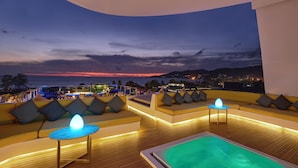 A rooftop lounge with a pool, seating areas, and a view of the sunset over the ocean. - The Kee Resort & Spa (Patong)
