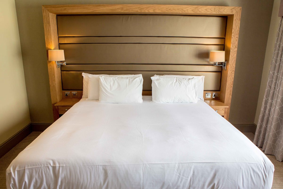 A hotel room with a large bed, two bedside tables, and a wooden headboard.