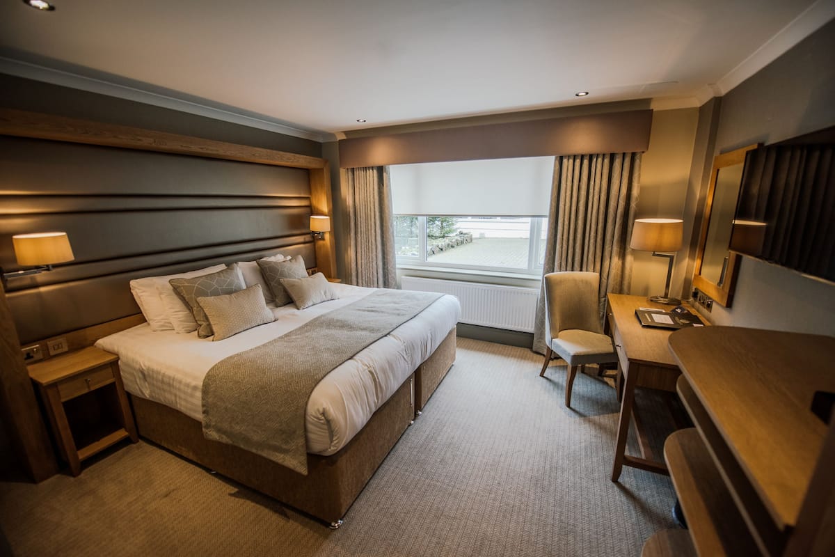 A hotel room with a large bed, bedside tables, a desk, and a chair.