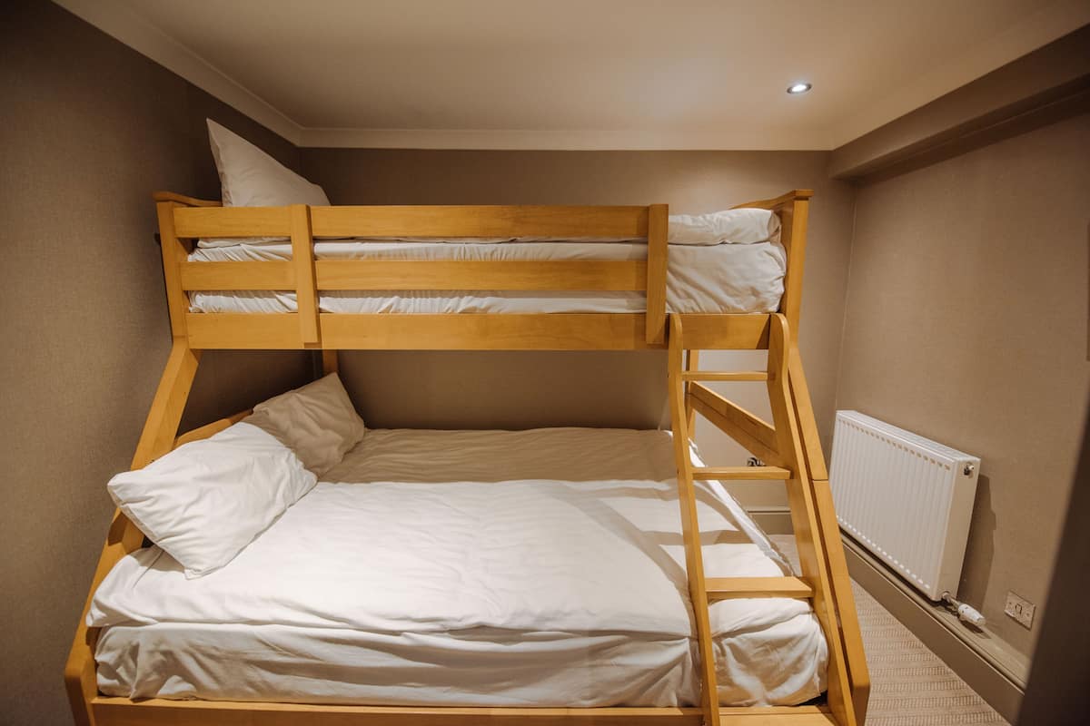 A bunk bed with a wooden frame and white bedding.