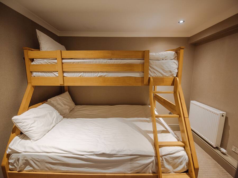 Una cama litera con estructura de madera y ropa de cama blanca.