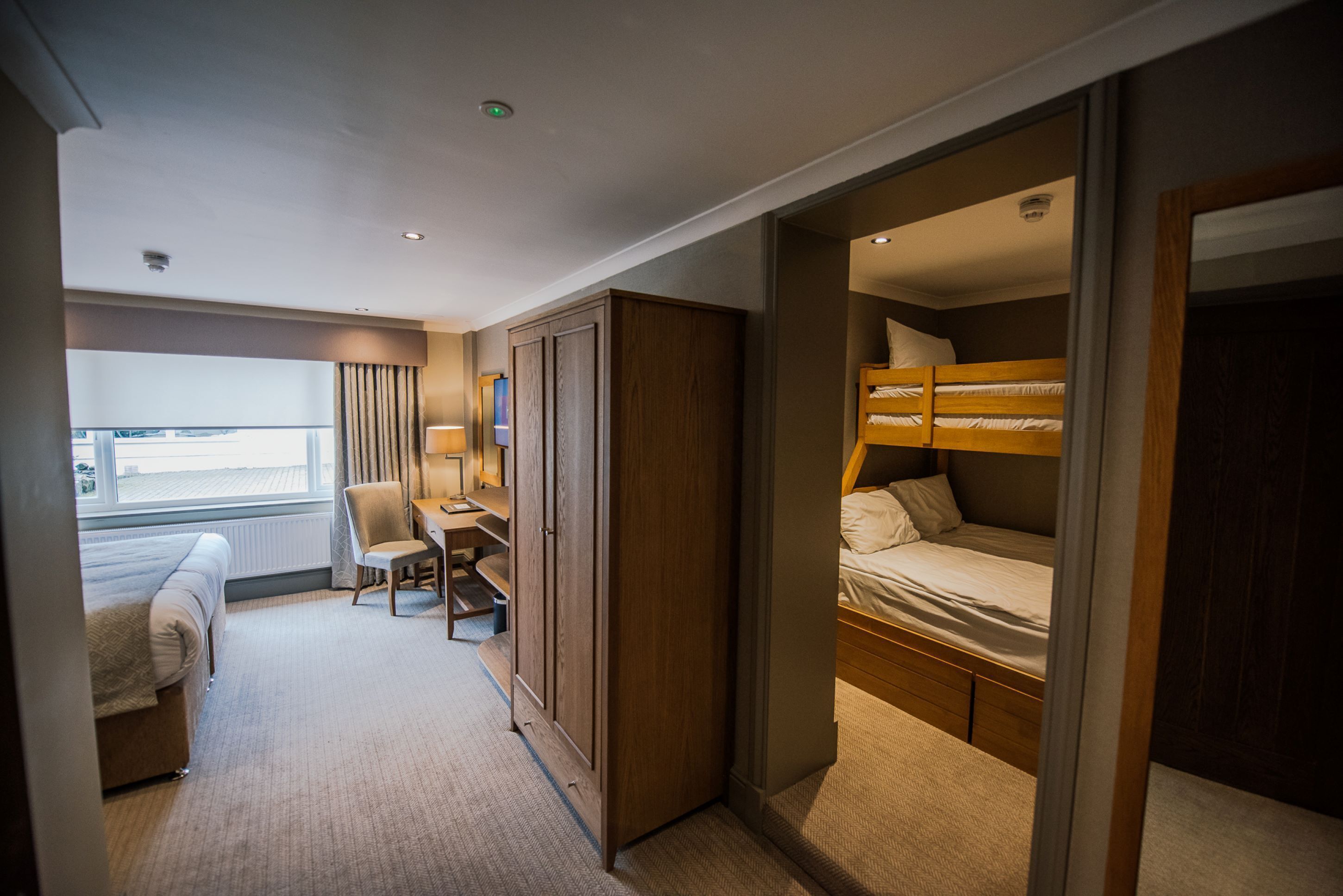 A hotel room with a bed, a desk, a chair, and a wardrobe.