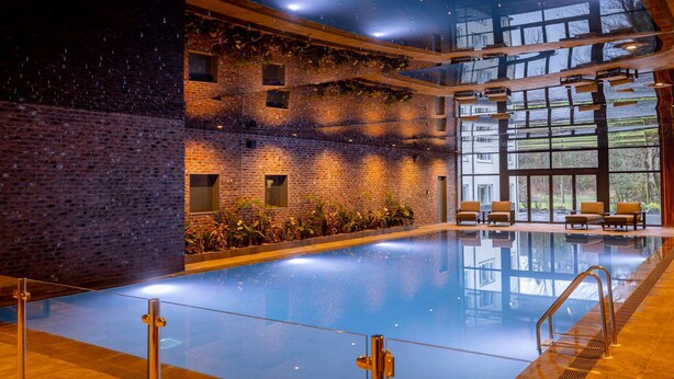A spacious indoor swimming pool with a brick wall and large windows. - Bowfield Hotel and Spa (Johnstone)