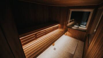 A wooden sauna with a bench and a window.