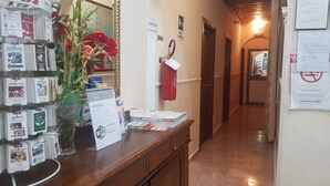 A hotel reception area with a wooden counter displaying various brochures and a fire extinguisher. - Aristotele Hotel (Rome)